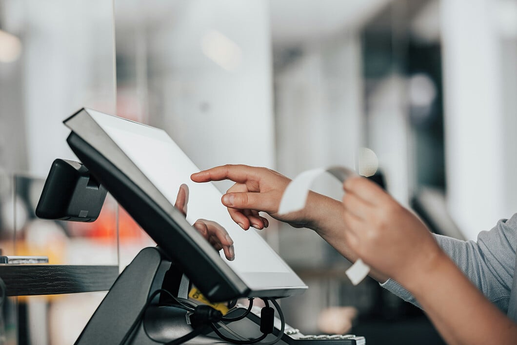 A person using a POS machine at a store checkout